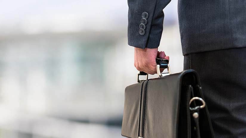 Detail of a businessman holding a leather briefcase