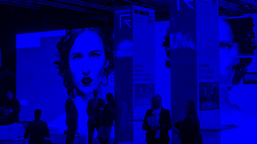 Blue treatment to image of event stand at Sibos with large LED screen displaying images of twins and a number of people standing around in the Refinitiv stand