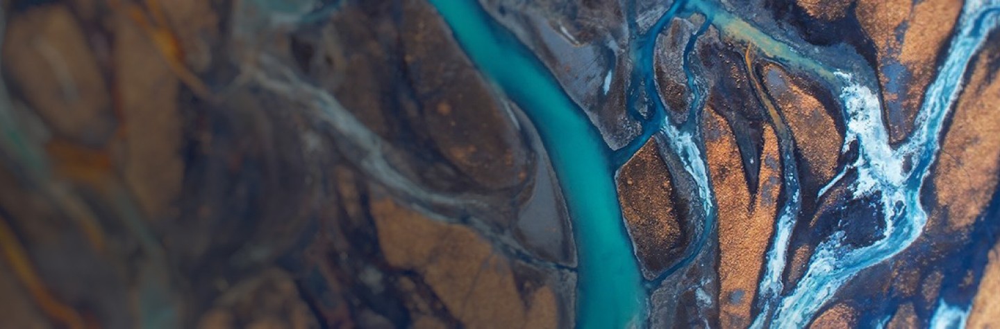 Aerial view of meandering turquoise streams over brown landscape in Iceland