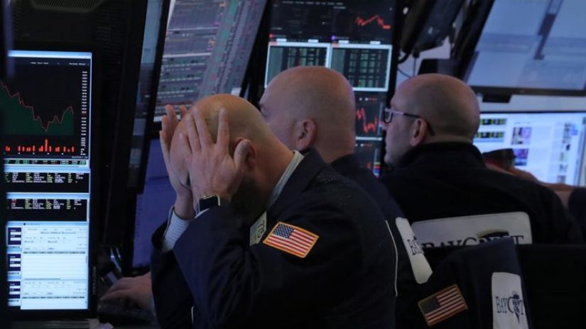 A trader putting his head in his hands with screens in front of him visualizing insights from data. 