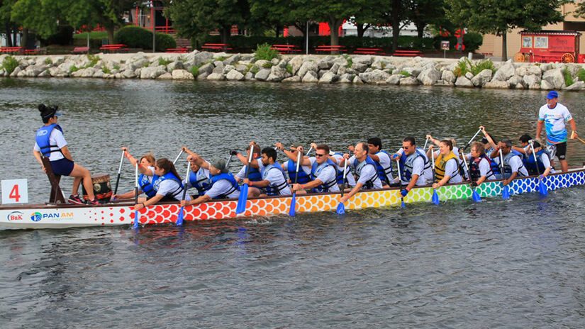A group of people row in a dragon boat on a lake