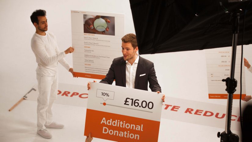 A Refinitiv employee holding a banner with additional donation of £16 written on it, thereby displaying his TicketAid initiative.