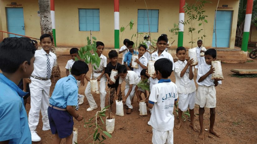 A group on Indian boys gathered together to plant trees on the ground.